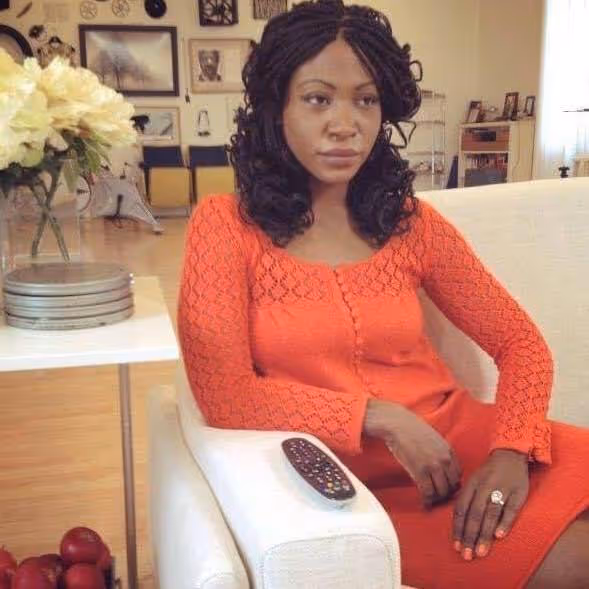 Africa Yoon, seated in an orange dress beside white flowers and film-reel canisters